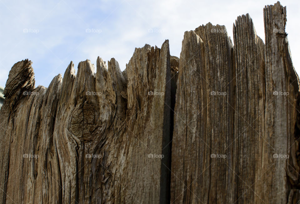 Old wooden fence weathered over time against blue sky 