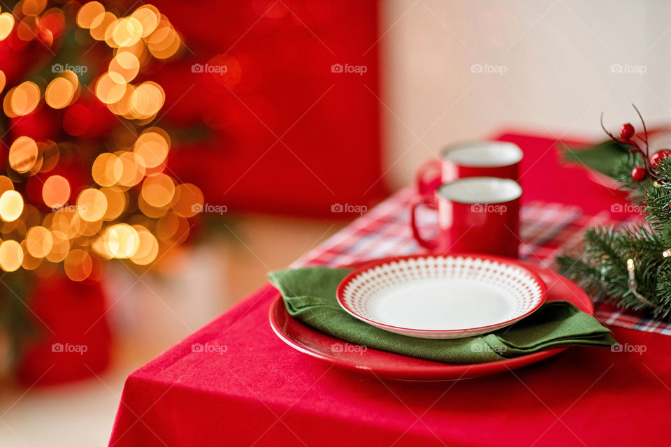 Festive winter cozy kitchen interior with garlands, decorations and gifts.  Christmas dinner at the decorated table.