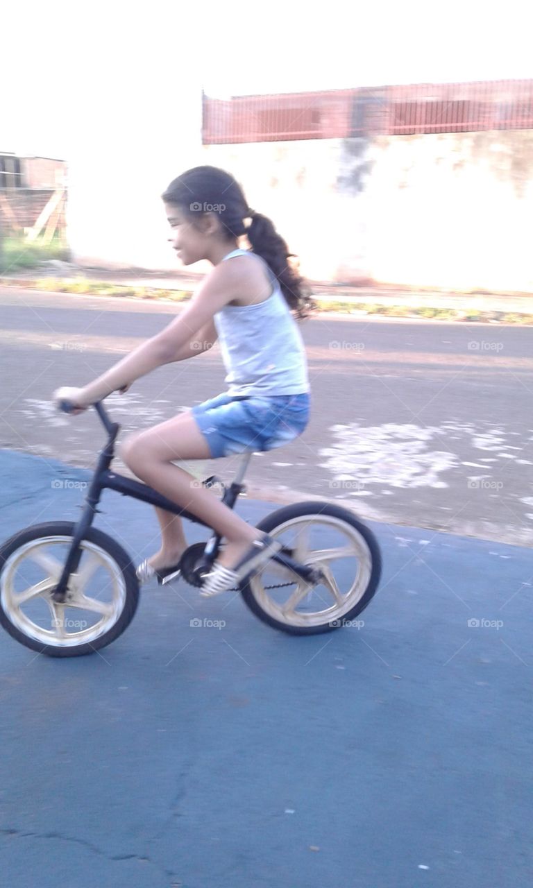 alegria de uma criança andando em simples bicicleta de mostrando que pra ser feliz precisar de muito