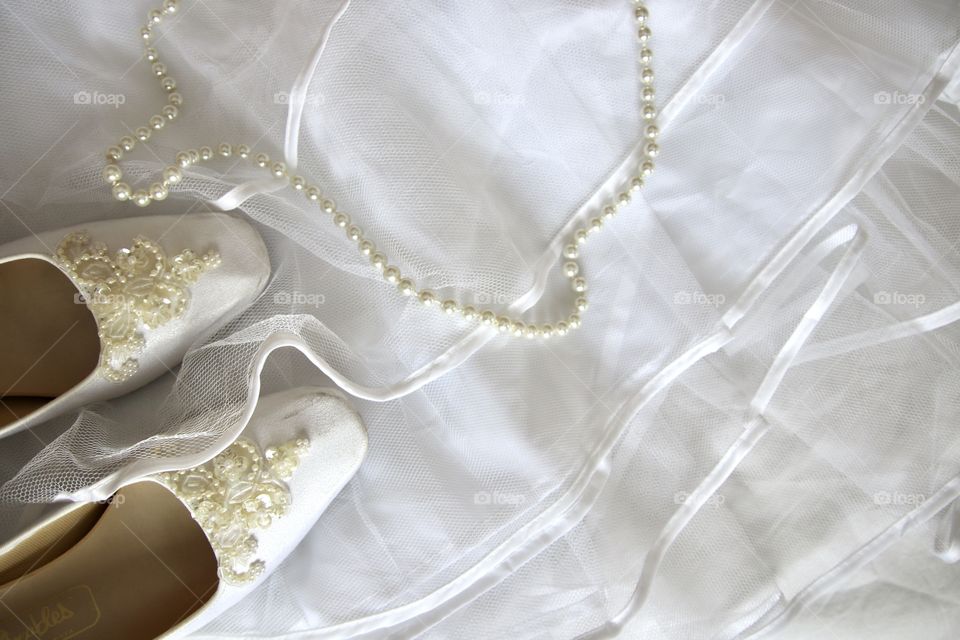 Flat-lay of wedding shoes pearls and white tulle