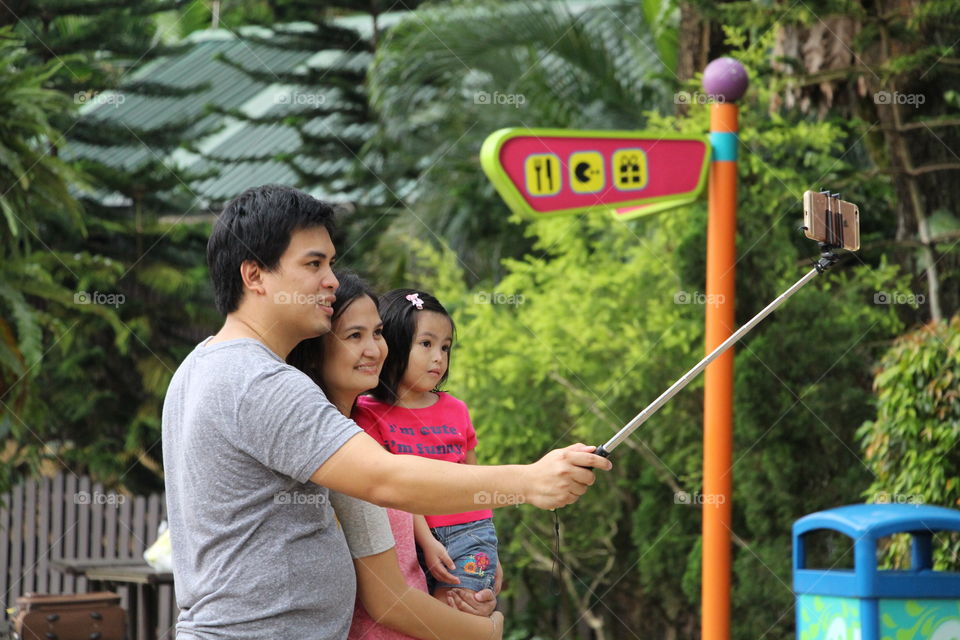 Family takes wefie with a selfie stick.