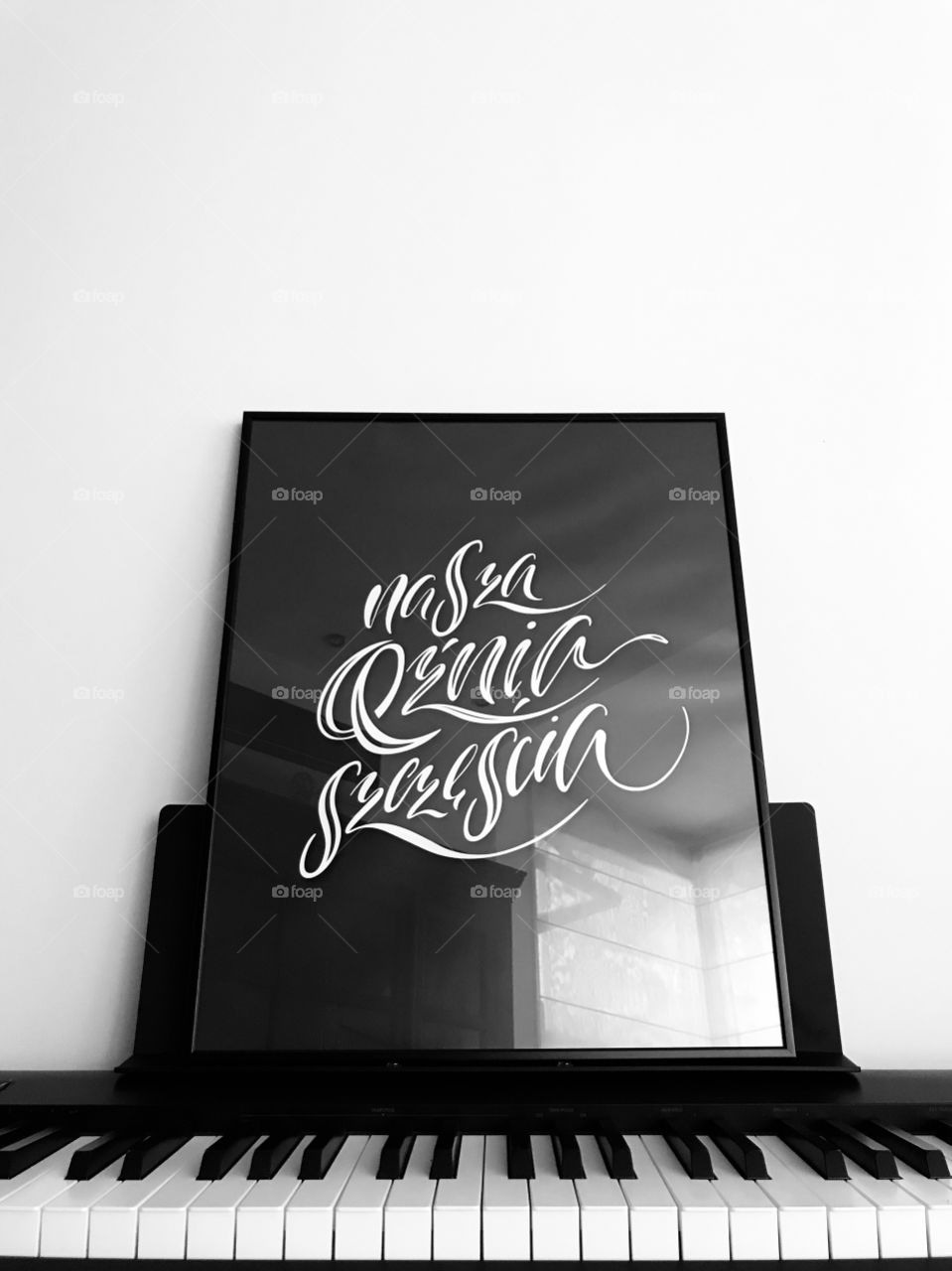 „Nasza kuźnia szczęścia”, a minimalist black and white poster on piano 