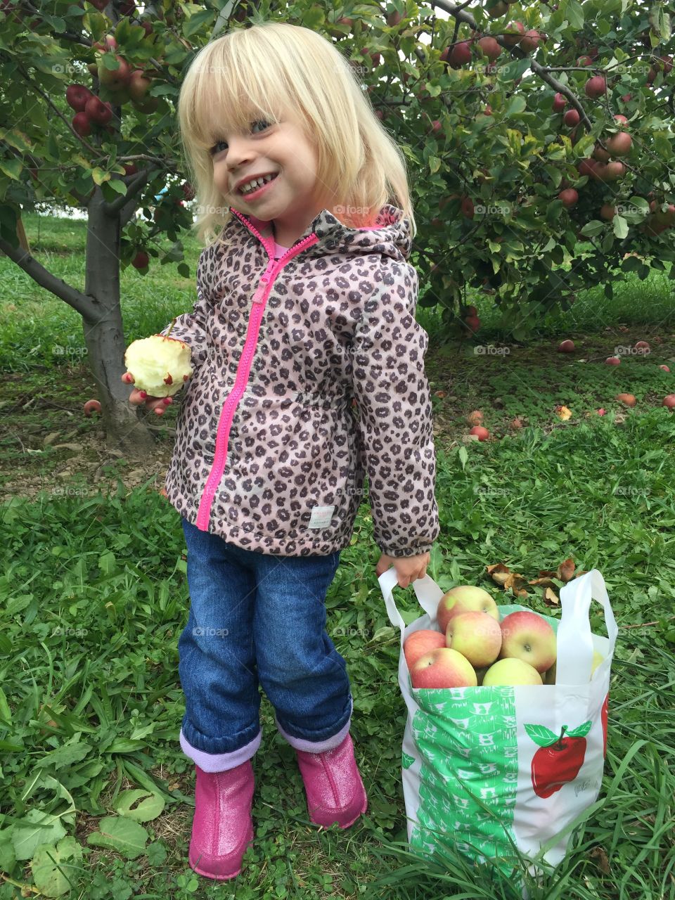 Girl standing with many apples in plastic bag