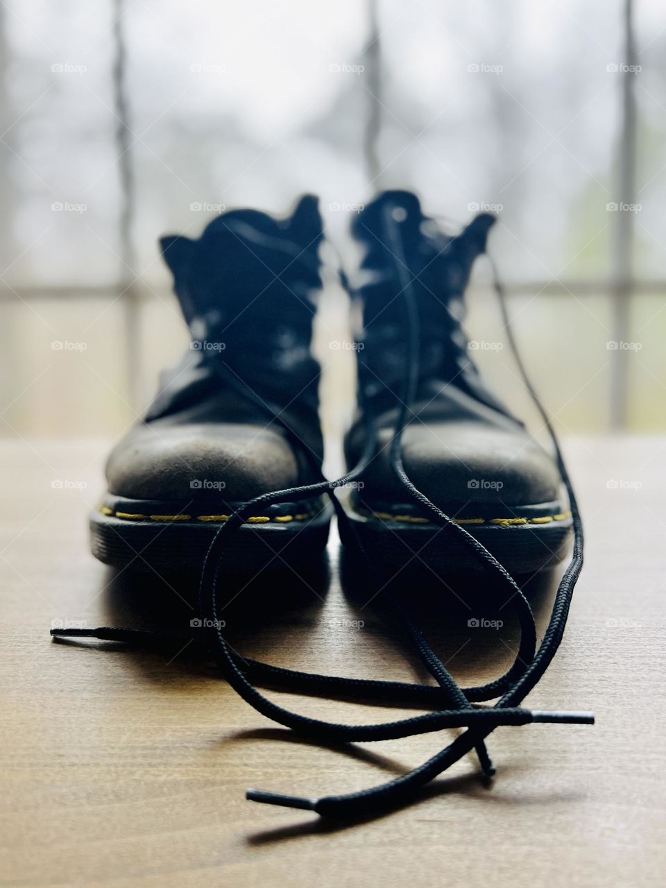 Closeup pair of worn classic Doc Marten boots backlit by window