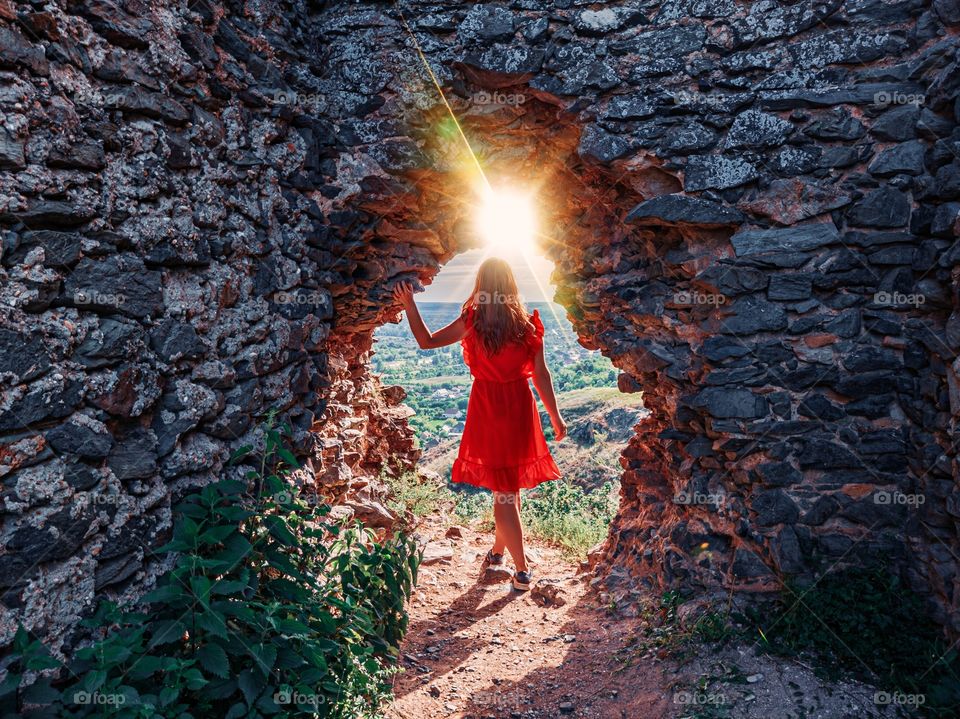 Woman in red between the ruins sunset