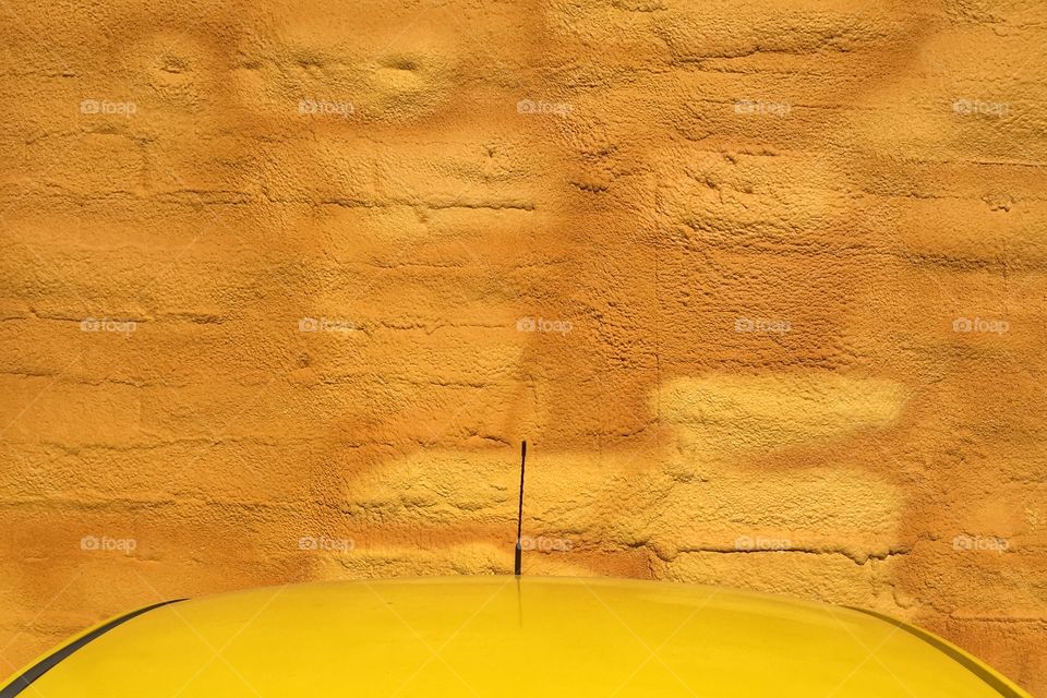 Yellow car parked in front of a yellow wall