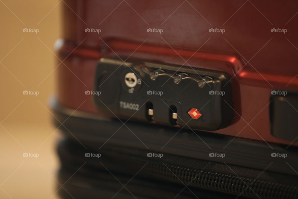Red  suitcase with focus on TSA approved combination lock. 