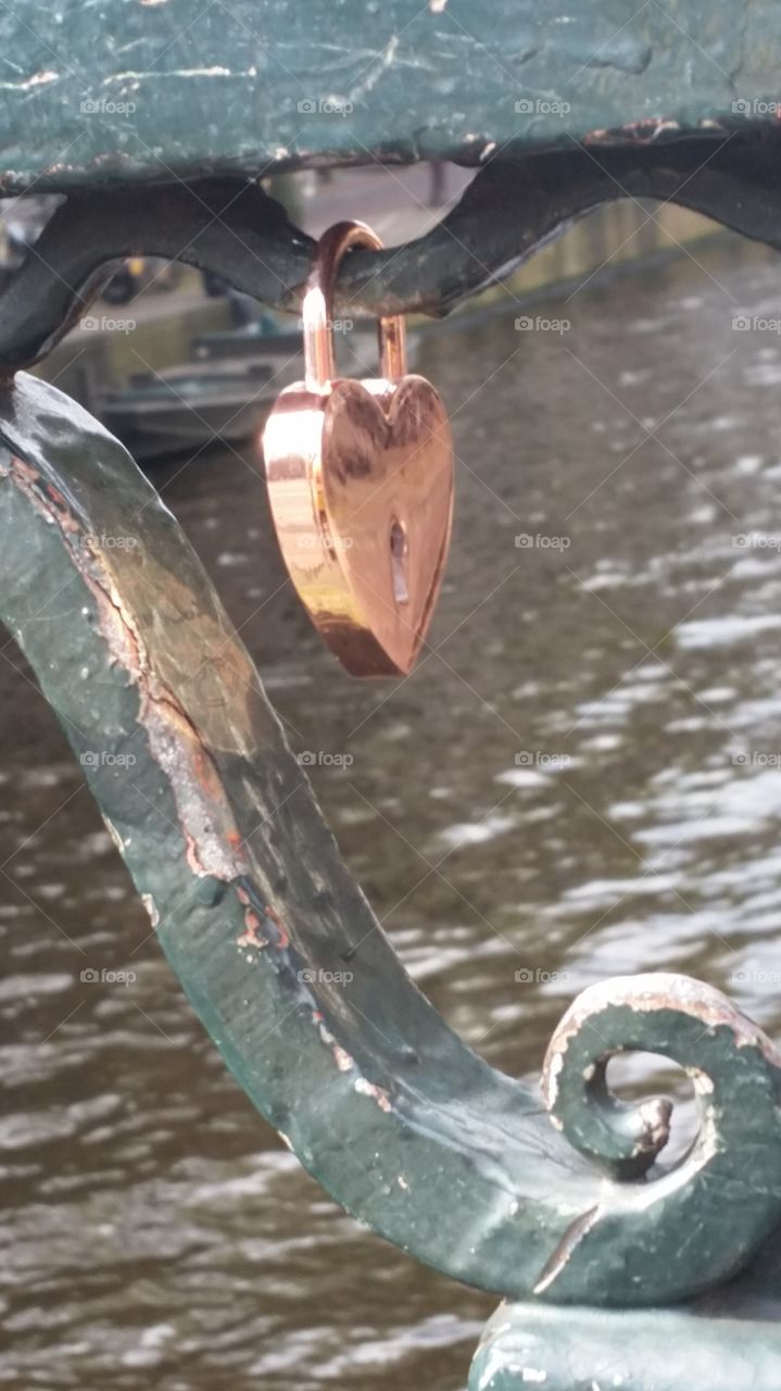 a golden lock hanging on a bridge in amsterdam,  a token of love