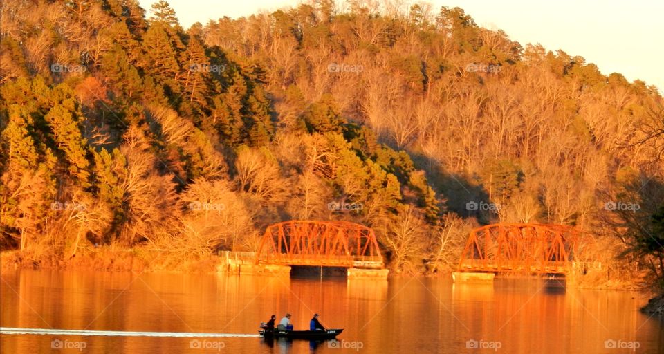 boat on lake with broken bridge in background, golden color