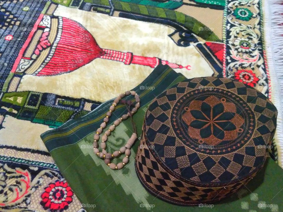 Cap and sarong on prayer rug