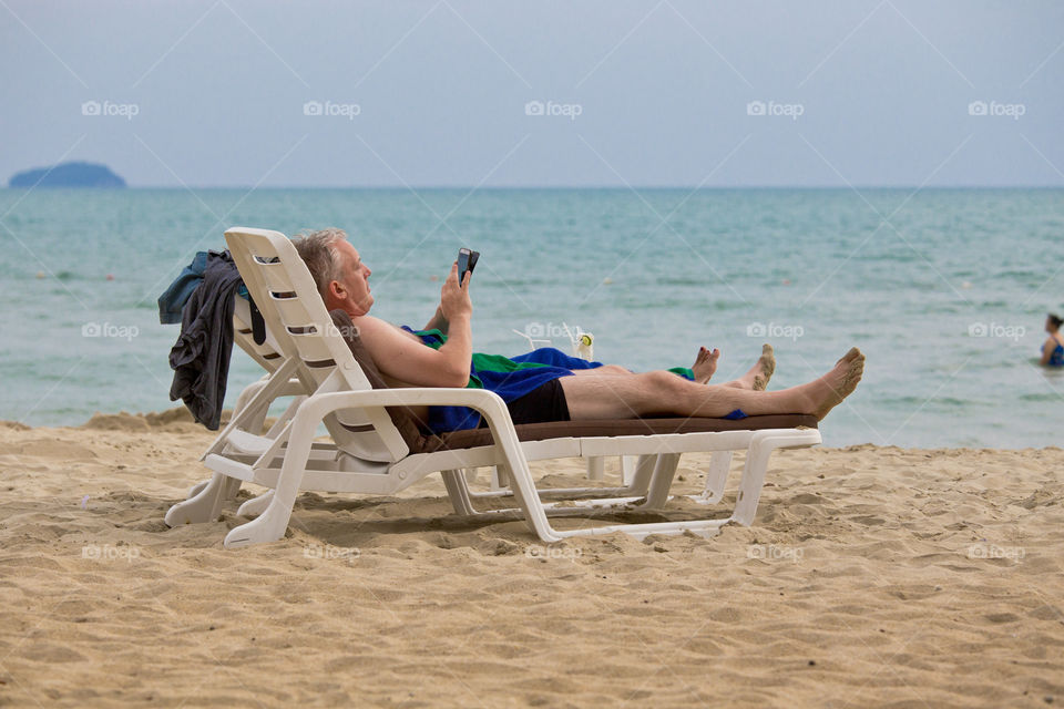 Tourist working by the beach. man reading his tablet