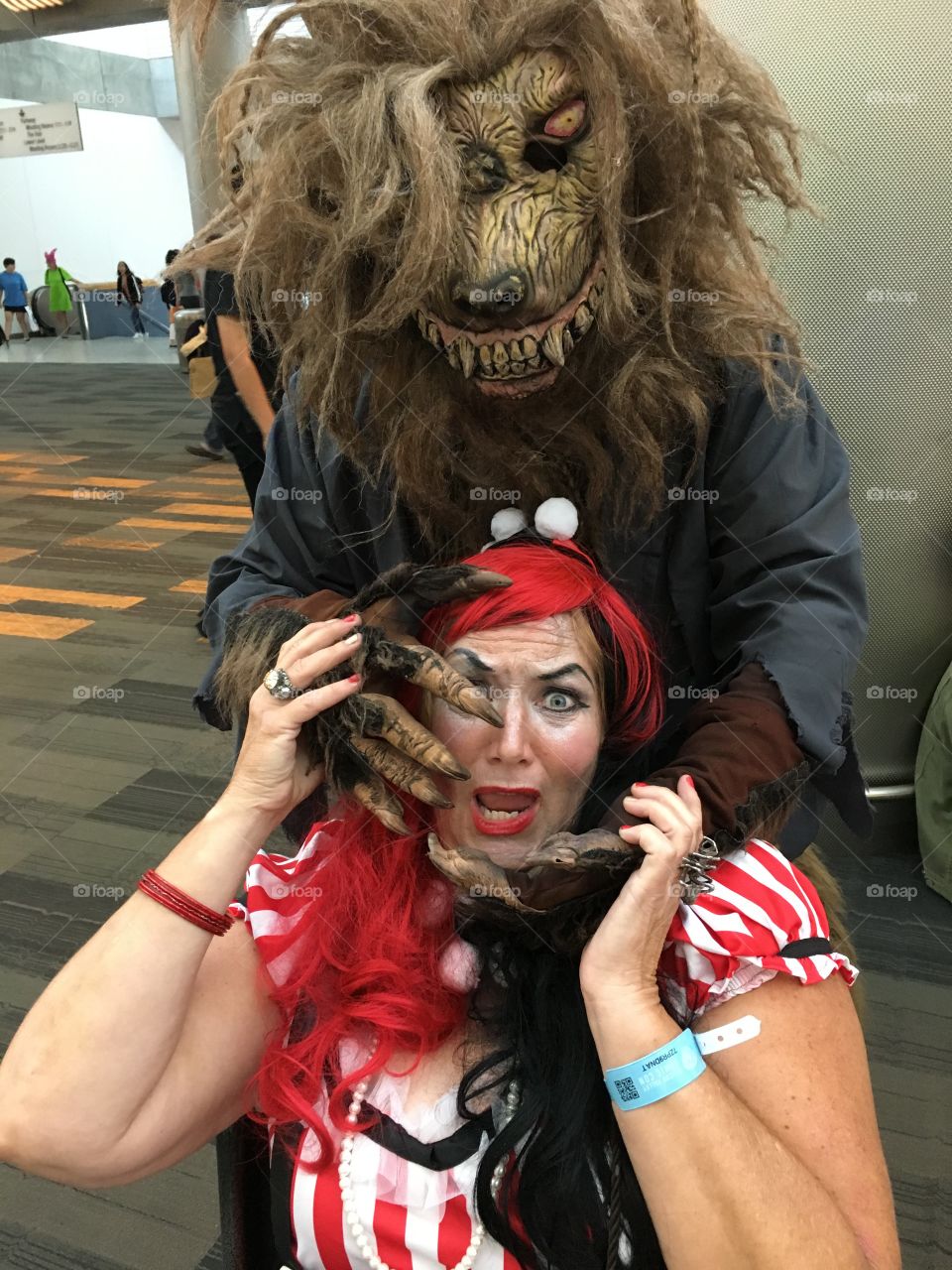 Harley Quinn at San Jose Comicon being attacked by a horrific monstrous werewolf who is trying to devour her with his menacing sharp teeth 
