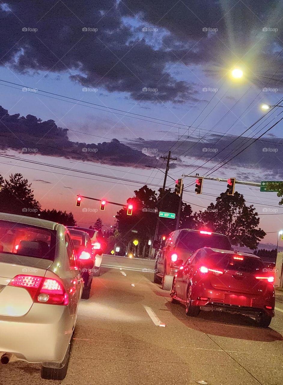 cars lined up at a red stoplight on a cloudy night in Oregon weekend commuter traffic