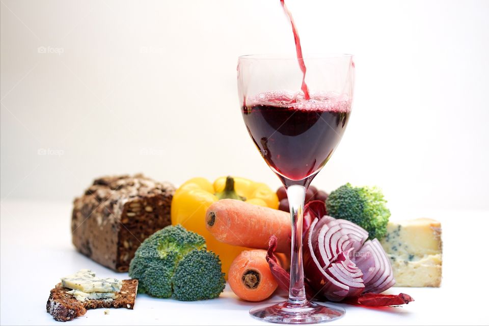 Vegetables and red wine over white background