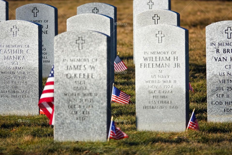 American flags surround certain headstones in a veterans graveyard commemorating their sacrifice