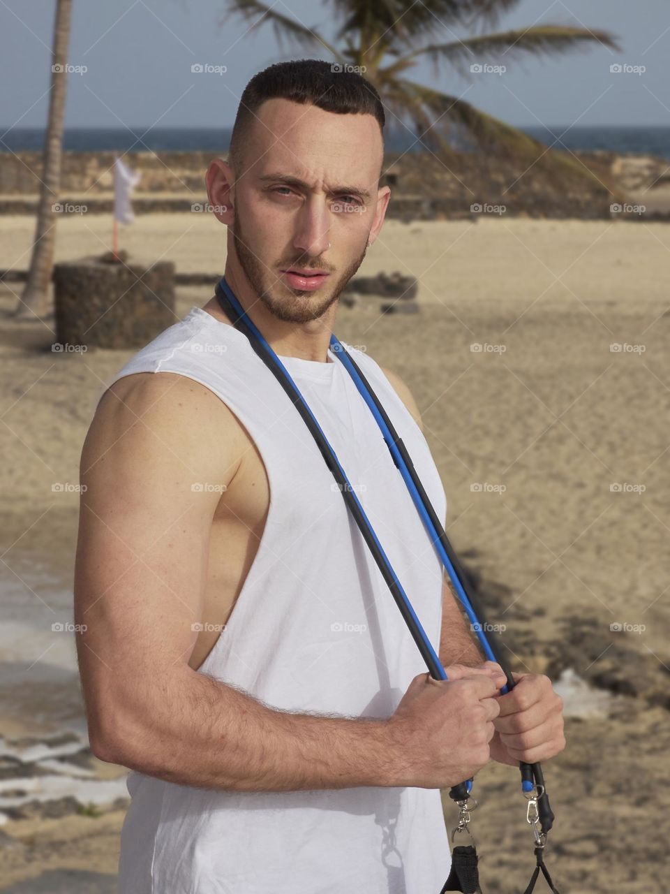 man training in the street doing various exercises with elastic band and overlooking the sea
