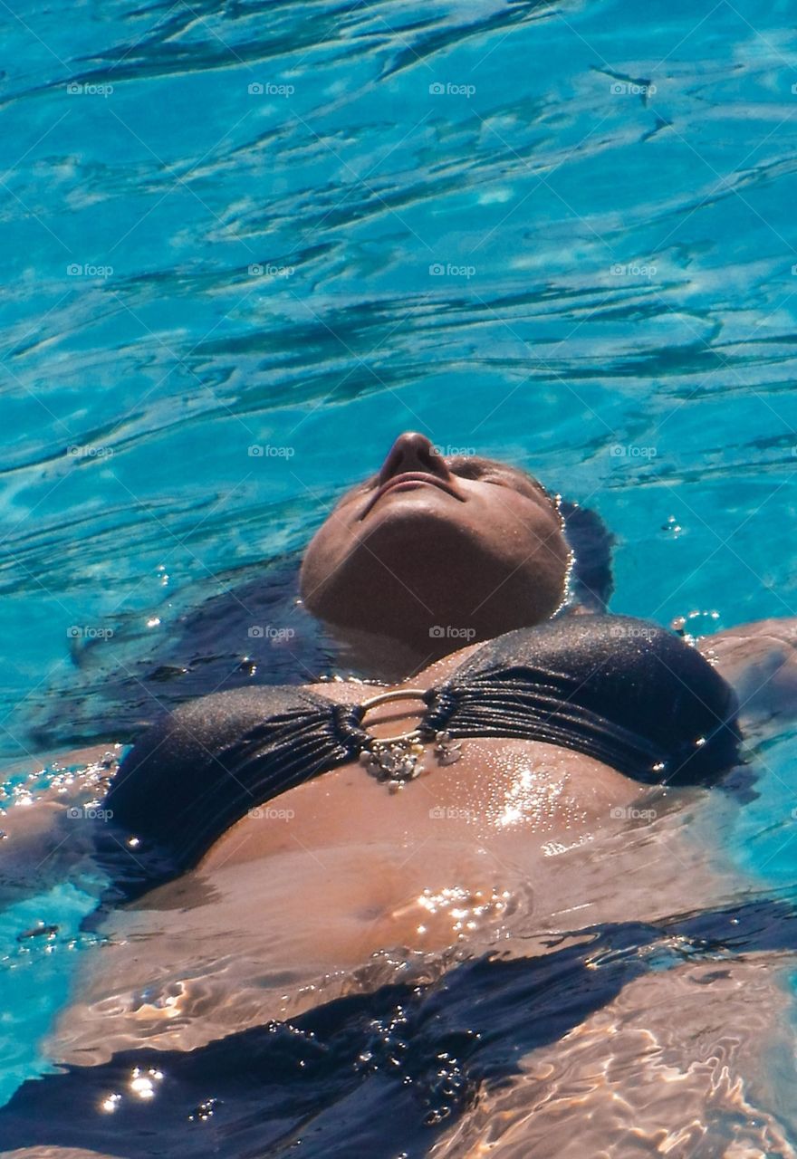 Close up of a woman floating into the pool