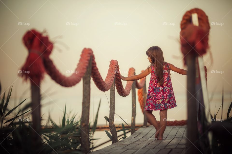 Little girl near lake at sunset