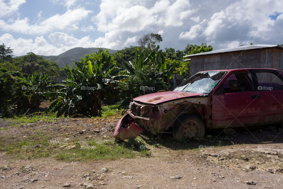 Broken and rusty car left abandoned in lush environment in the outskirts of Boston Bay in Portland parish, Jamaica on 30 December 2013.