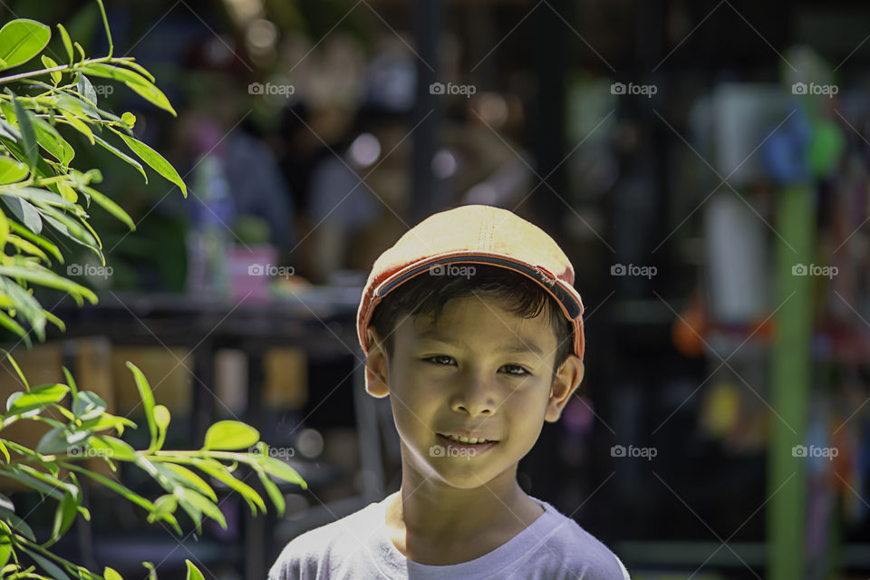 Portrait of Asian boy wearing a red cap and white  shirt is smile and Play water mist.