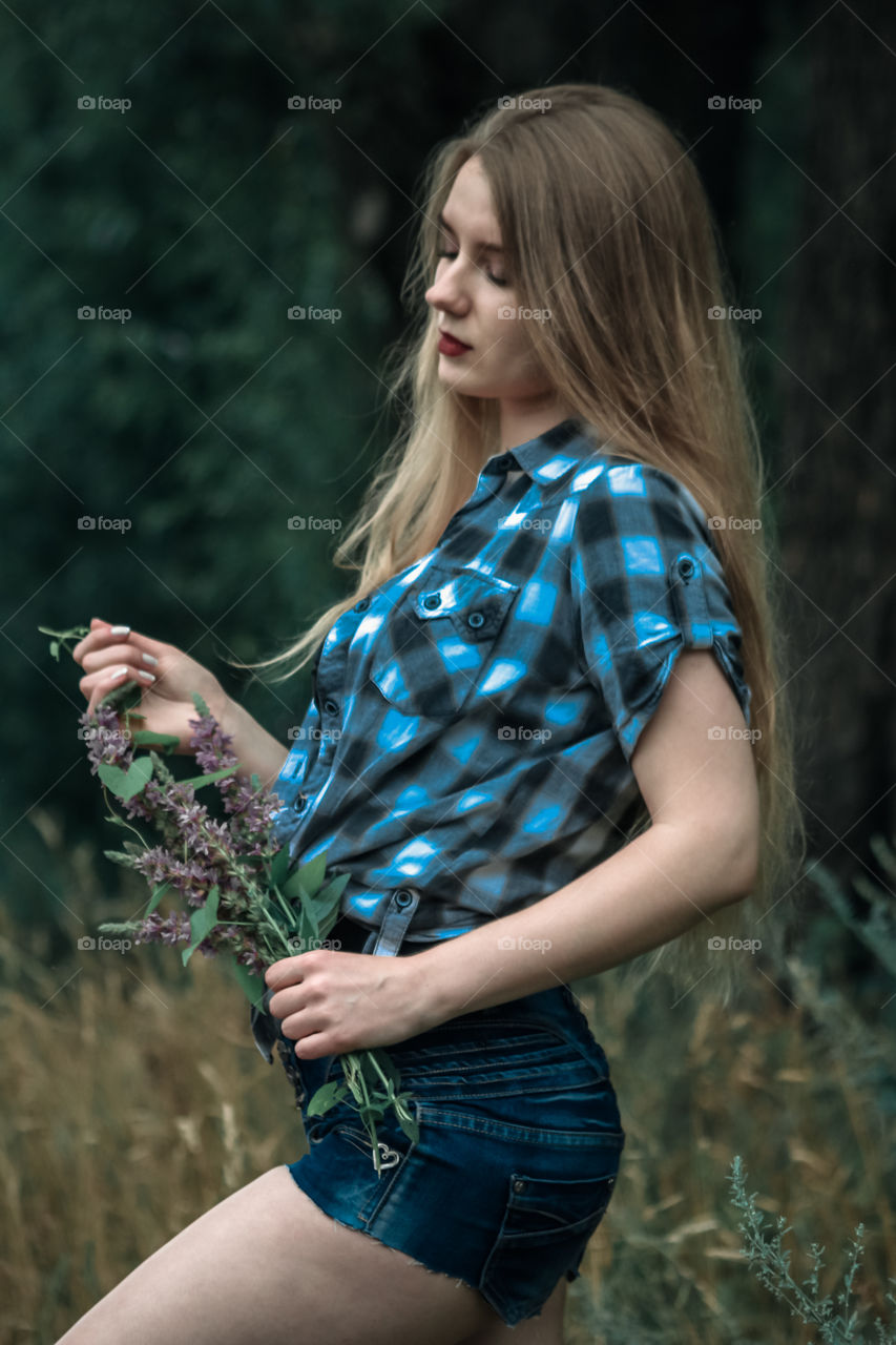 A girl with blond hair in a plaid shirt and short denim shorts on a background of trees and nature,
Girl, woman, man, people, blonde, blonde hair, checkered shirt, shorts shorts, denim shorts, forest, nature, trees, grass, feelings, emotions, tenderness, love, lifestyle, lifestyle, recreation