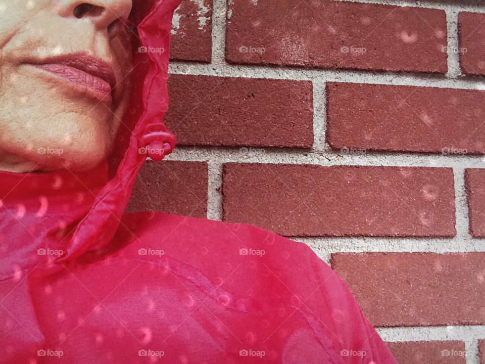 Woman in her red rain coat protected by the rain.