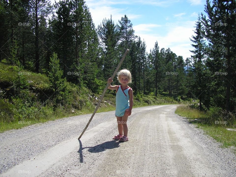 Girl with a stick on a gravelled road