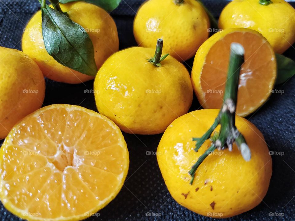 Fresh orange fruits with leaves as background, top view