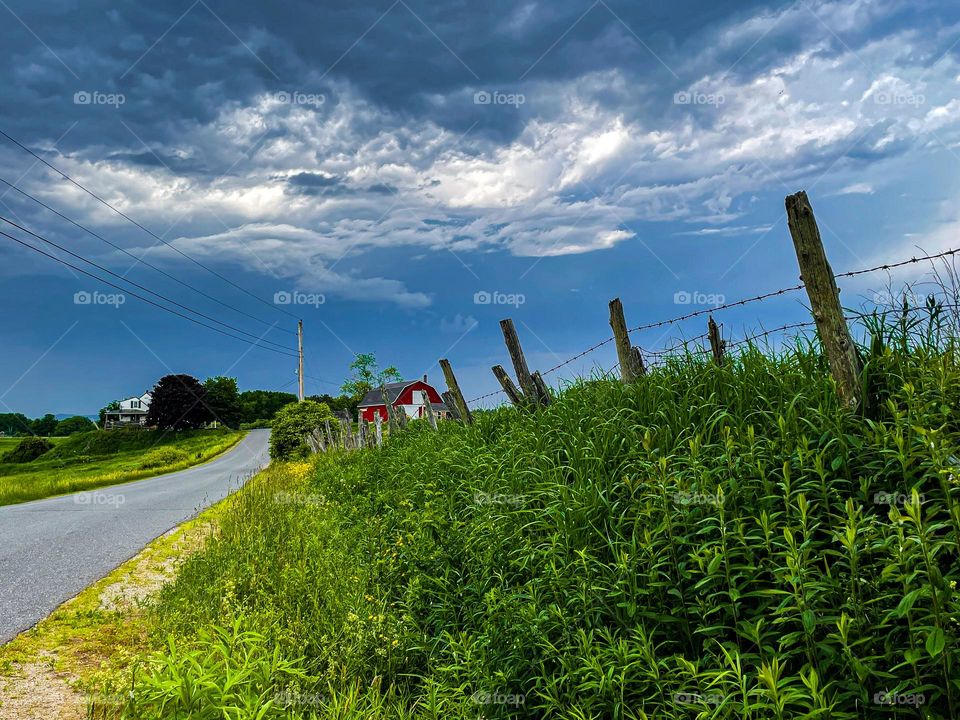 “Incoming Storm.”  Dark clouds roll over a farm meadow.