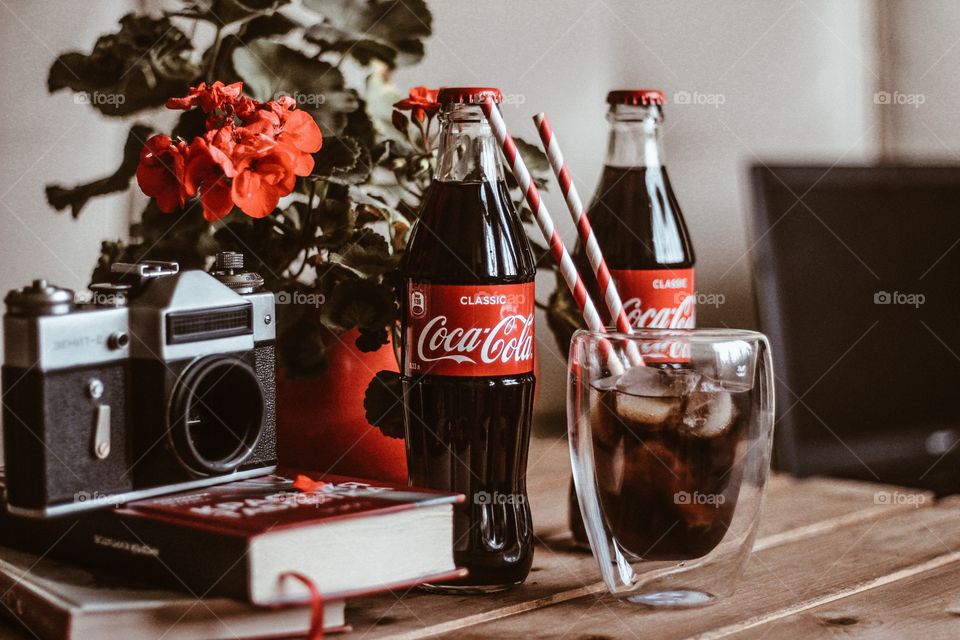 two bottles of coca-cola and a glass with a straw on the table