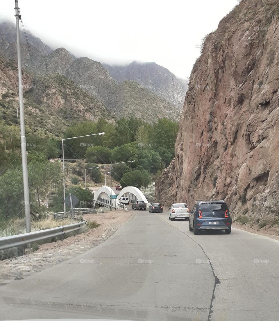 varios autos van por la ruta y cruzarán el puente en la montaña