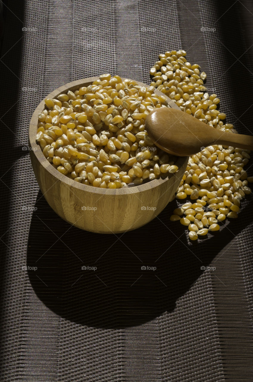 corn seeds in a bowl with spoon and brown tones