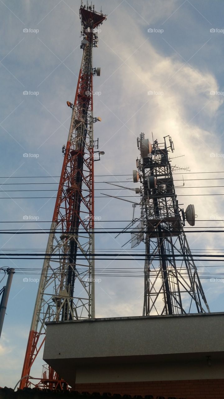 Low angle view of communication tower against cloudy sky