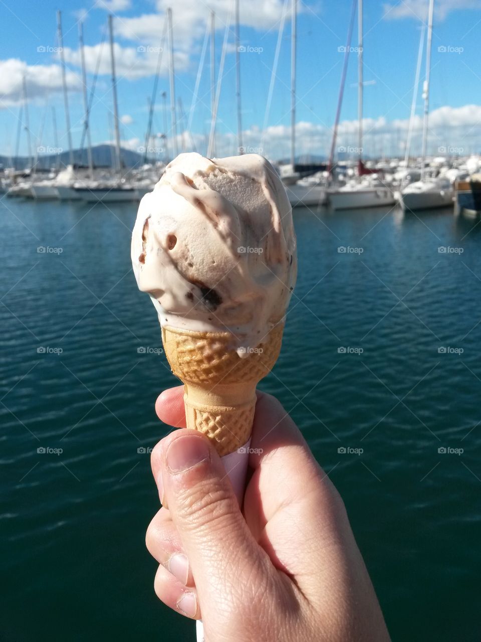 fresh  ice cream held by a hand in front of the sea