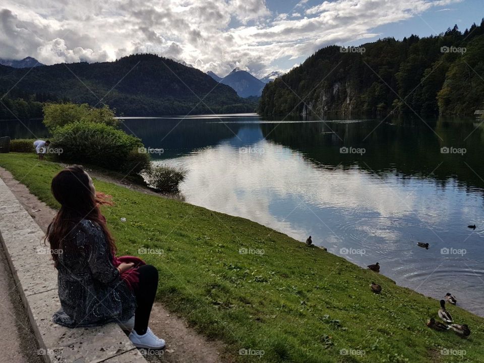 Füssen. View of the lake and mountains of fussen. It is possible to see the reflection of the trees and mountains in the lake and a woman admiring 
