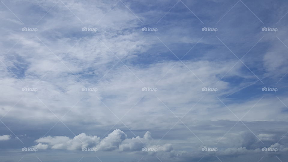 White clouds stretch across a beautiful blue sky.