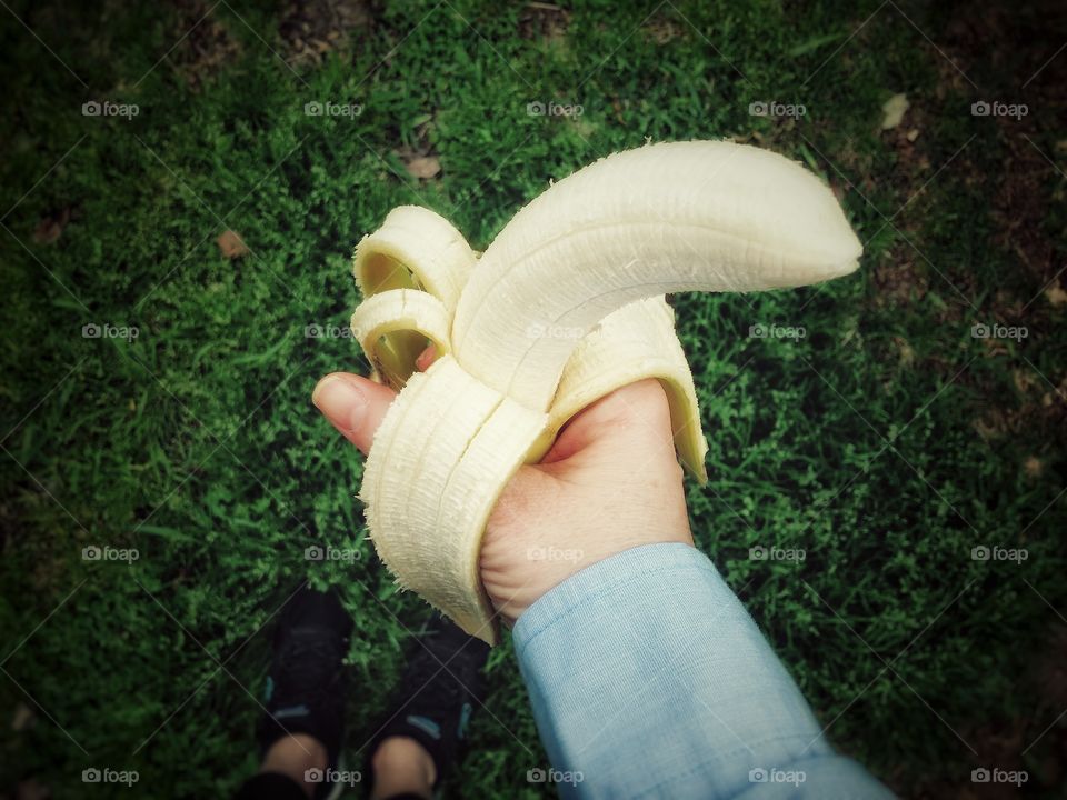 Woman standing in the green grass holding a peeled banana