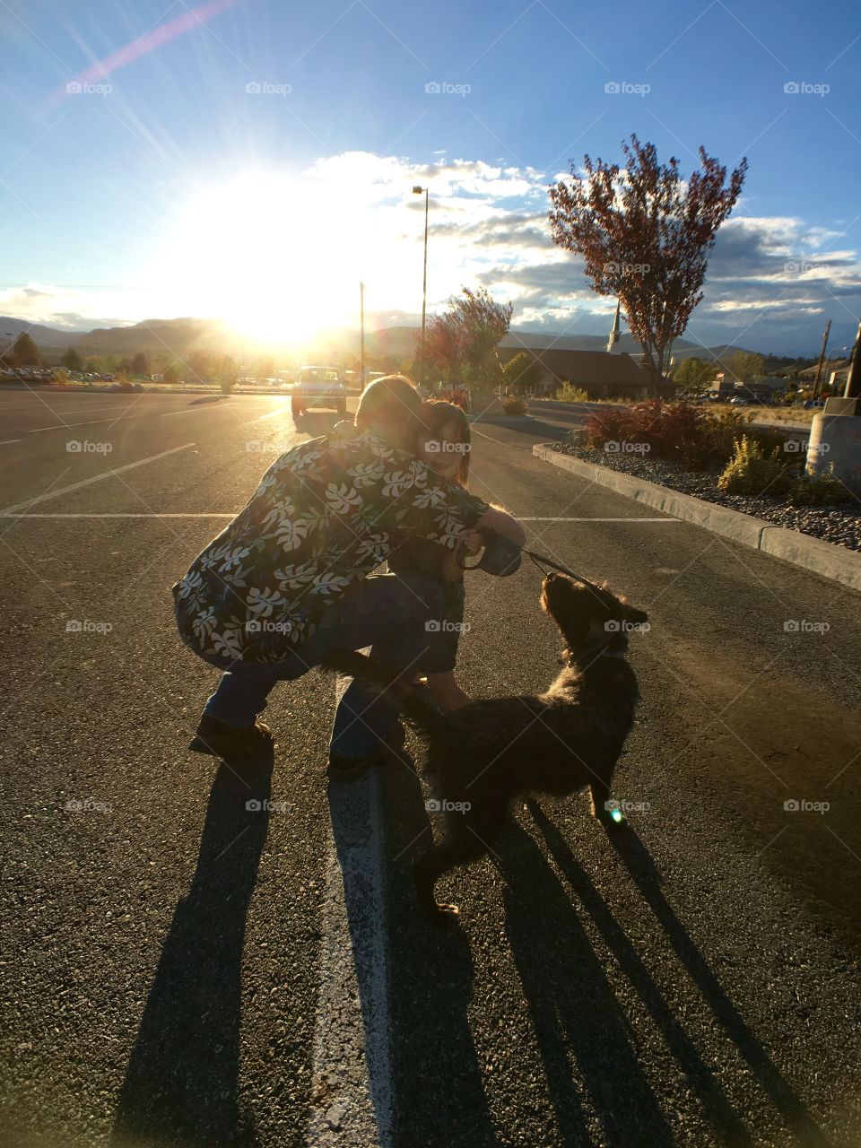 Father hugging her daughter with dog in street