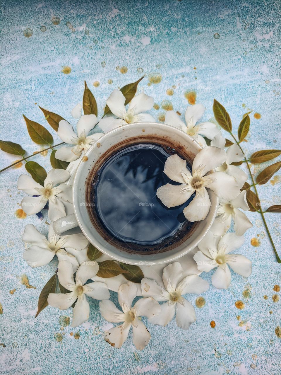 Background of a cup of hot coffee on the table with beautiful flowers close-up. Top view.
