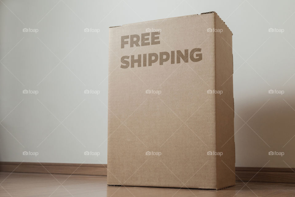 Cardboard box with written free shipping order placed on the floor in front of the house door at the time of delivery with the house door in the background. free delivery concept. transport concept.