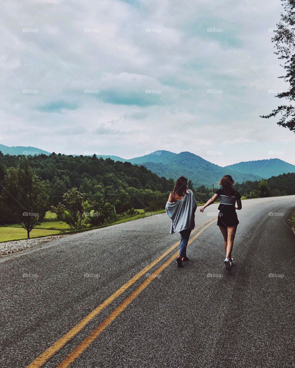 Two girls walking on a long road to nowhere