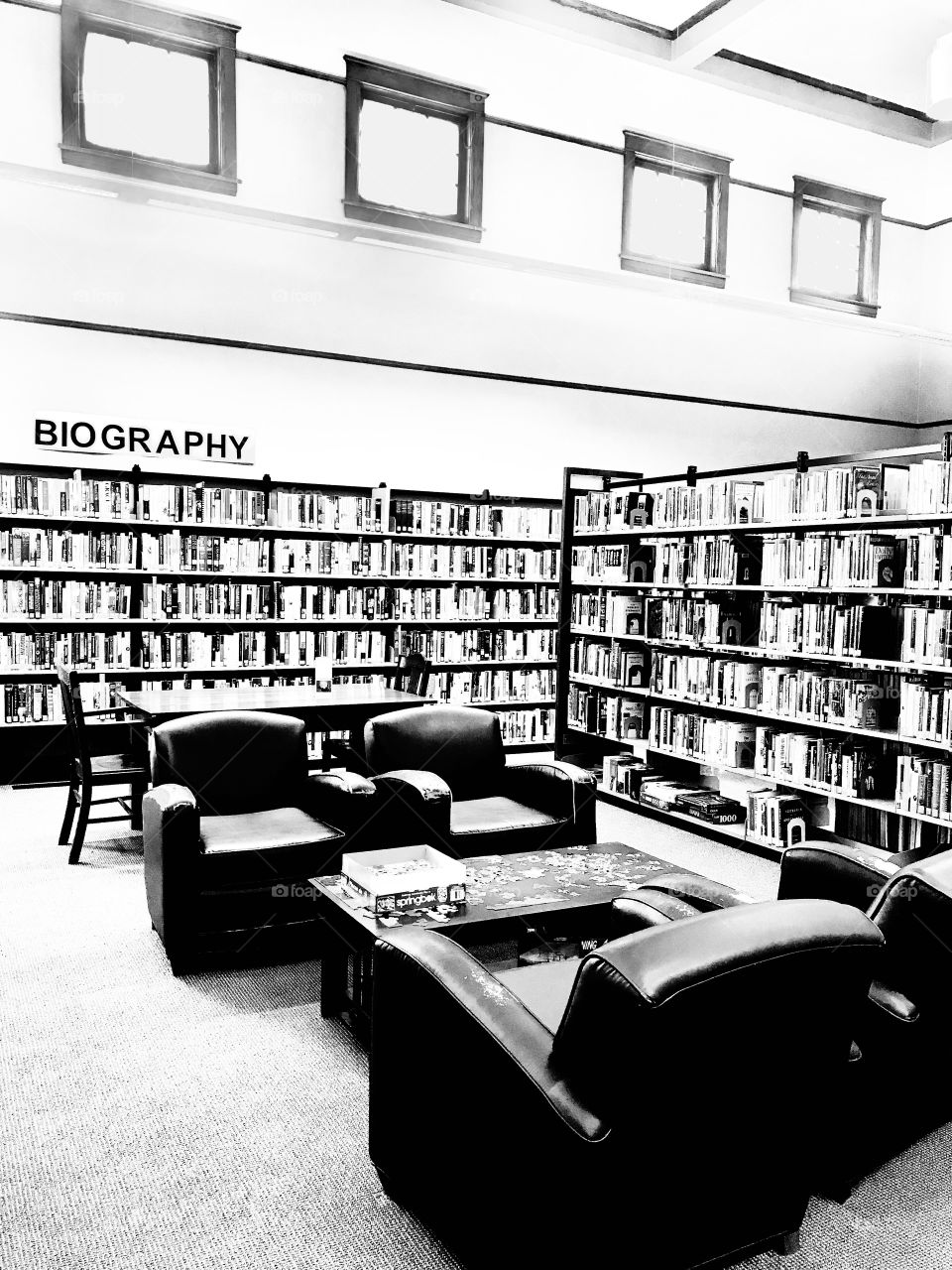 Interesting black and white photo of long row of bookshelves full of library books. 