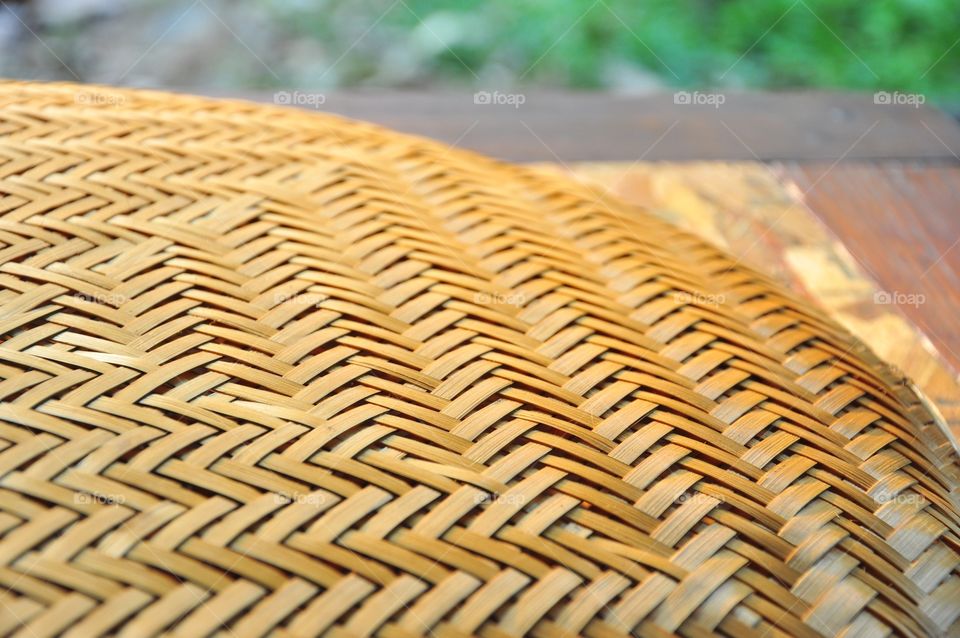 Brown woven bamboo closeup texture. Wicker texture. Winnowing or threshing basket on the table. Woven bamboo pattern. Arrow pattern texture. Abstract texture.