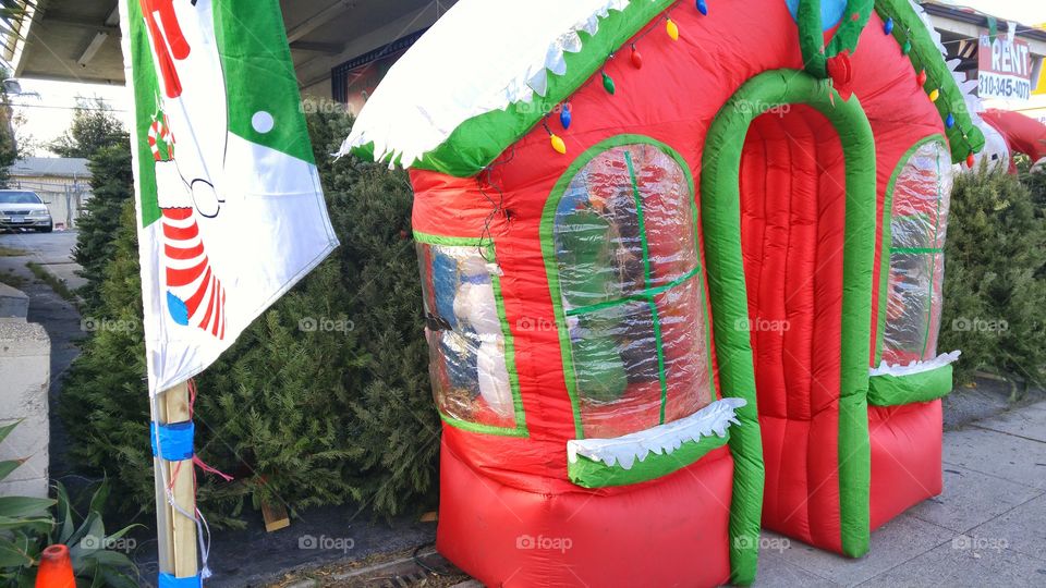 Inflated Christmas decoration/house in front of Christmas trees