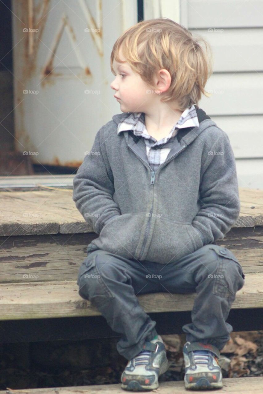 Sad boy sitting on wooden plank