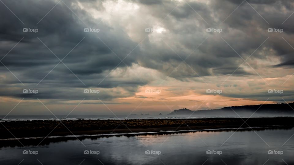 Storm clouds over river at sunset