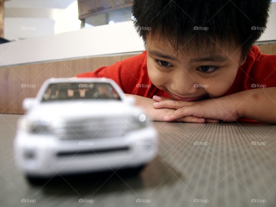 Boy looking at white toy car