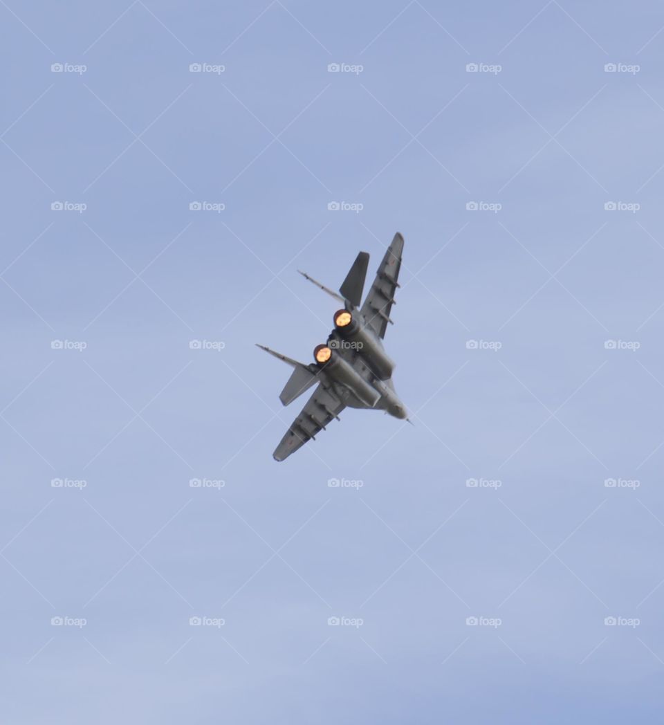 The plane is flying against the blue sky. Aerobatic figure, military aircraft.