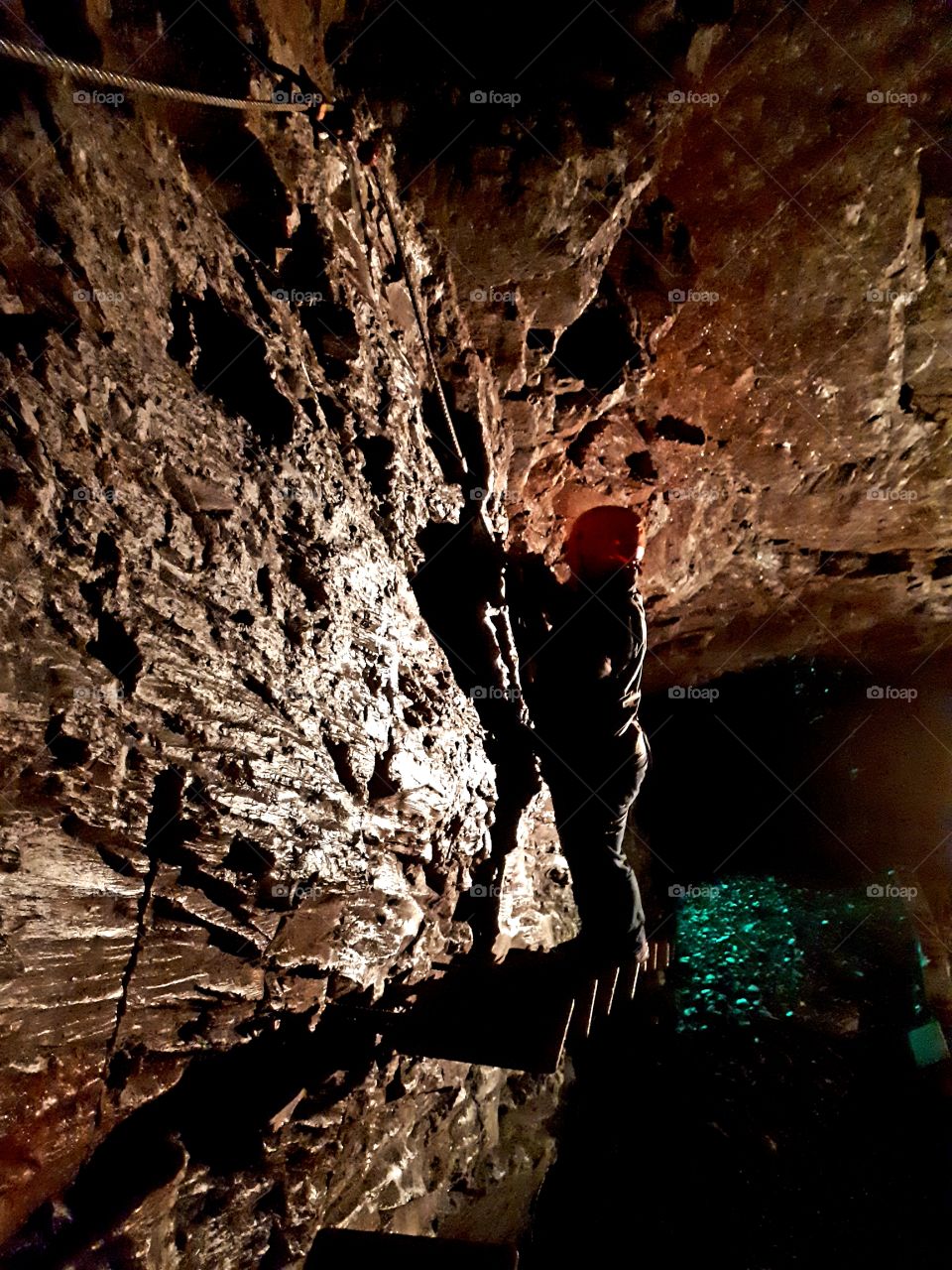 Person climbing along rock in slate cave.