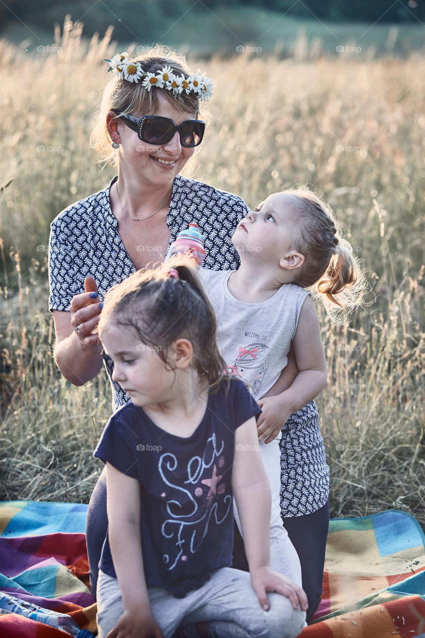 Family spending time together on a meadow, close to nature. Parents and children playing together, making coronet of wild flowers. Candid people, real moments, authentic situations